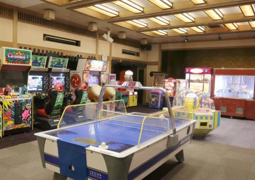 a room with several arcade games and a table at Uomisaki Hotel in Atami