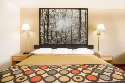 a bed in a hotel room with a picture of trees at Super 8 by Wyndham Lexington VA in Lexington