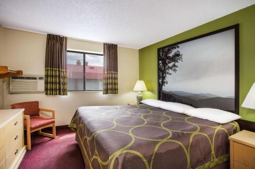 a small hotel room with a bed and a chair at Super 8 by Wyndham Salem VA in Salem