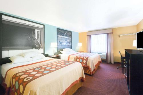 a hotel room with two beds and a flat screen tv at Super 8 by Wyndham Richmond in Richmond