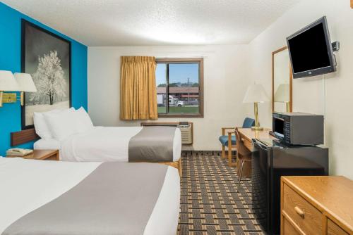 a hotel room with two beds and a flat screen tv at Super 8 by Wyndham Lincoln West in Lincoln