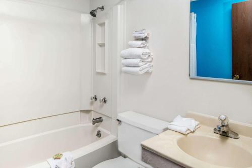 Super 8 by Wyndham Lincoln West في لينكولن: حمام أبيض مع حوض ومرحاض وحوض استحمام