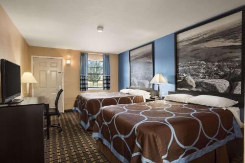 a hotel room with two beds and a flat screen tv at Super 8 by Wyndham Henryetta in Henryetta