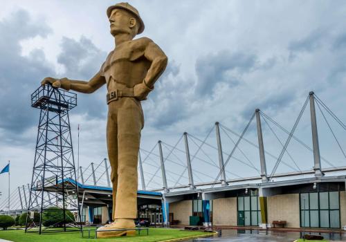 a statue of a man standing in front of a stadium at Super 8 by Wyndham Tulsa/Arpt/St Fairgrounds in Tulsa