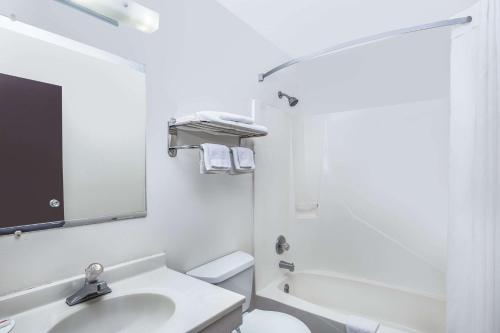 a bathroom with a sink and a toilet and a mirror at Super 8 by Wyndham Columbus in Columbus