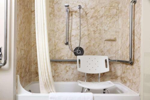 a shower with a white chair in a bathroom at Super 8 by Wyndham Idaho Falls in Idaho Falls