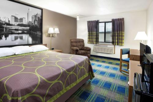 コロンバスにあるSuper 8 by Wyndham Columbusのベッドと椅子付きのホテルルーム
