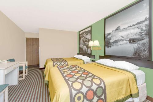ein Hotelzimmer mit 2 Betten und einem großen Bildschirm in der Unterkunft Super 8 by Wyndham Lexington in Lexington