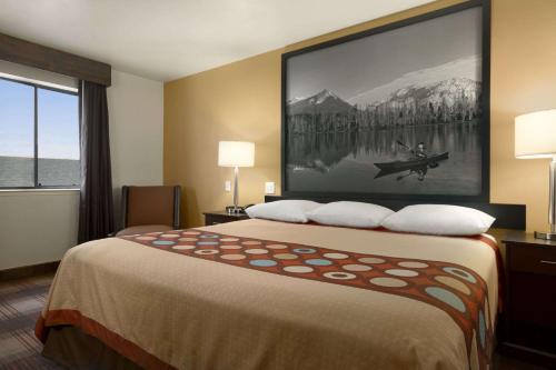 a hotel room with a bed with a large painting on the wall at Super 8 by Wyndham Idaho Falls in Idaho Falls