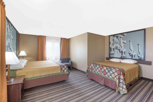 a hotel room with two beds and a desk at Super 8 by Wyndham Natchitoches in Natchitoches
