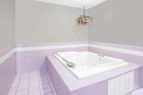 uma casa de banho branca com uma banheira com um arranjo de flores em Super 8 by Wyndham Howe em Howe