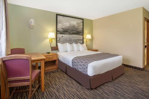 a hotel room with a bed and a desk and chair at Super 8 by Wyndham Lewistown in Lewistown