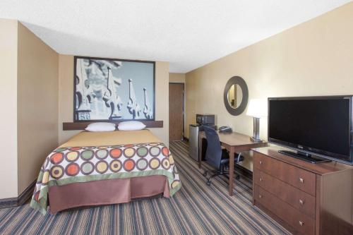 a hotel room with a bed and a desk and a flat screen tv at Super 8 by Wyndham Natchitoches in Natchitoches