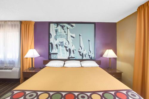 a large bed in a room with two lamps at Super 8 by Wyndham Natchitoches in Natchitoches