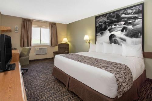 a hotel room with a bed and a flat screen tv at Super 8 by Wyndham Lewistown in Lewistown
