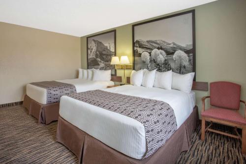 a hotel room with two beds and a chair at Super 8 by Wyndham Lewistown in Lewistown