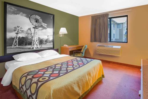 a hotel room with a bed and a painting of a windmill at Super 8 by Wyndham Howe in Howe