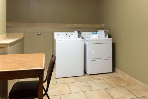 una pequeña cocina con nevera blanca y mesa en Super 8 by Wyndham Radcliff Ft. Knox Area, en Radcliff