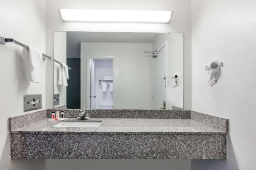 a bathroom with a sink and a large mirror at Super 8 by Wyndham Sapulpa/Tulsa Area in Glenpool