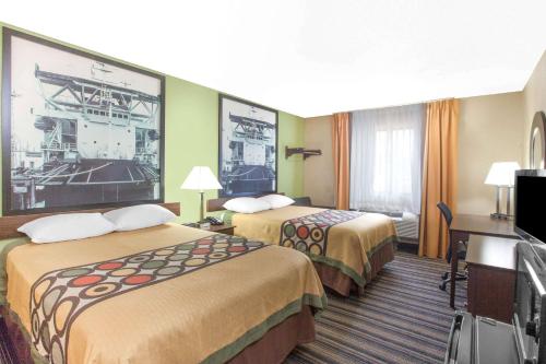 a hotel room with two beds and a television at Super 8 by Wyndham Natchitoches in Natchitoches