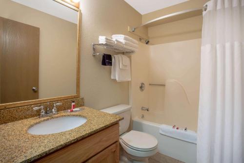 a bathroom with a sink and a toilet and a mirror at Super 8 by Wyndham Lewistown in Lewistown