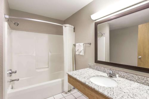 a bathroom with a sink and a tub and a mirror at Super 8 by Wyndham Plymouth in Plymouth