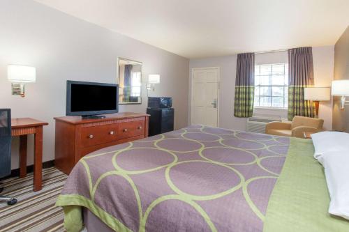 a hotel room with a bed and a flat screen tv at Super 8 by Wyndham West Monroe in West Monroe