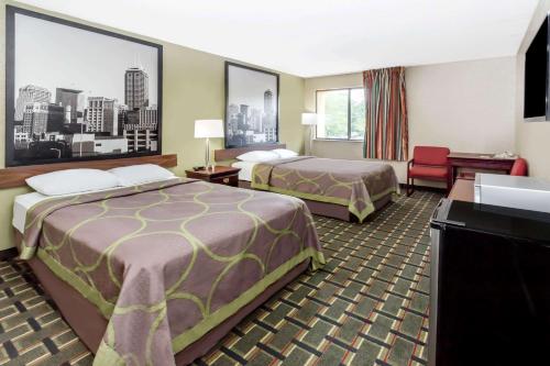 a hotel room with two beds and a desk at Super 8 by Wyndham Logansport in Logansport