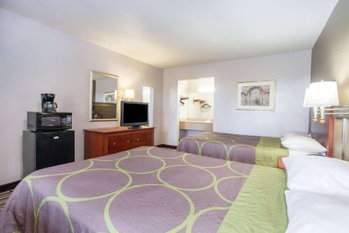 a hotel room with two beds and a flat screen tv at Super 8 by Wyndham West Monroe in West Monroe