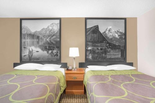 twee bedden in een hotelkamer met schilderijen aan de muur bij Super 8 by Wyndham Riverton in Riverton