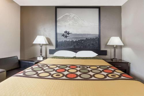 a bed in a hotel room with a painting on the wall at Super 8 by Wyndham Bremerton in Bremerton