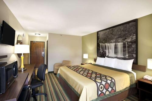 a hotel room with a bed and a flat screen tv at Super 8 by Wyndham Tuscola in Tuscola