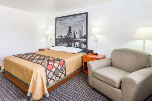 a small hotel room with a bed and a chair at Super 8 by Wyndham Rock Falls Sterling Area in Rock Falls