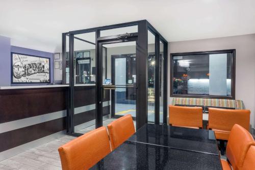 a dining room with a glass table and orange chairs at Super 8 by Wyndham Locust Grove in Locust Grove