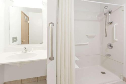a white bathroom with a shower and a sink at Super 8 by Wyndham Rock Falls Sterling Area in Rock Falls