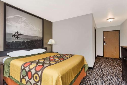 a hotel room with a large bed with a painting on the wall at Super 8 by Wyndham Bremerton in Bremerton