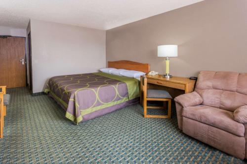 a hotel room with a bed and a desk and a chair at Super 8 by Wyndham St. Charles in Saint Charles