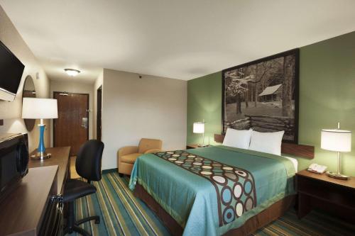a hotel room with a bed and a desk and a television at Super 8 by Wyndham Tuscola in Tuscola