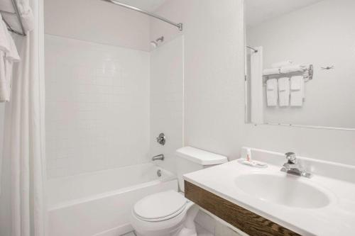 a white bathroom with a toilet and a sink at Super 8 by Wyndham Douglas in Douglas
