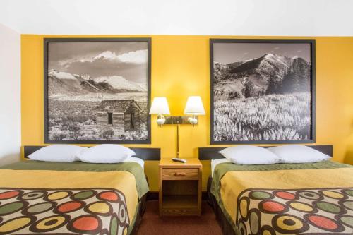 two beds in a hotel room with yellow walls at Super 8 by Wyndham Elko in Elko