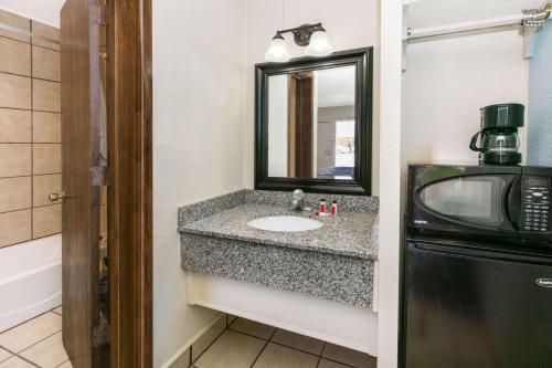 a bathroom with a sink and a microwave at Super 8 by Wyndham Lubbock Civic Center North in Lubbock