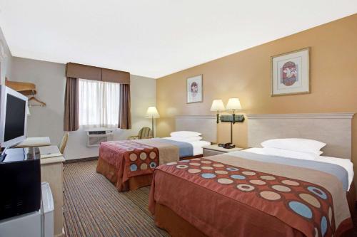 a hotel room with two beds and a flat screen tv at Super8 by Wyndham NEARBY Clearwater St Petersburg International Airport in Clearwater