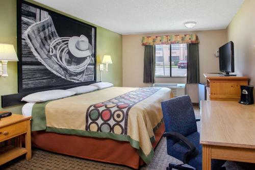 a hotel room with a bed and a desk and a chair at Super 8 by Wyndham Sherman in Sherman