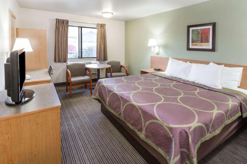 a hotel room with a bed and a flat screen tv at Super 8 by Wyndham Bend in Bend