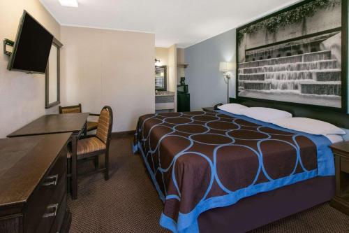 a hotel room with a bed and a desk at Super 8 by Wyndham Lubbock Civic Center North in Lubbock