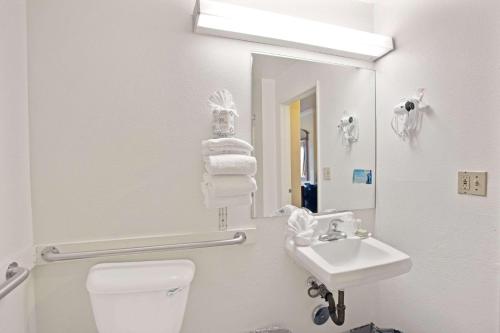 a bathroom with a toilet and a sink and a mirror at Super 8 by Wyndham Hollywood/LA Area in Los Angeles