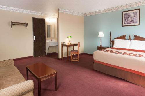 a hotel room with a bed and a couch at Super 8 by Wyndham Woodstock in Woodstock