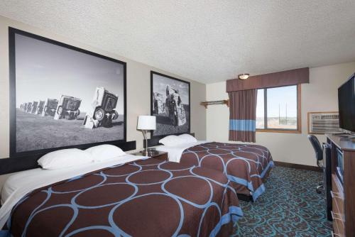 una habitación de hotel con 2 camas y una pantalla grande en Super 8 by Wyndham Tucumcari en Tucumcari