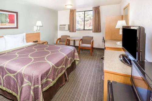 a hotel room with a bed and a flat screen tv at Super 8 by Wyndham Bend in Bend