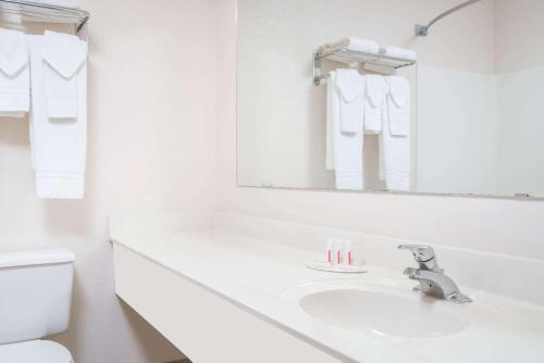 een witte badkamer met een wastafel en een spiegel bij Super 8 by Wyndham Sheldon in Sheldon